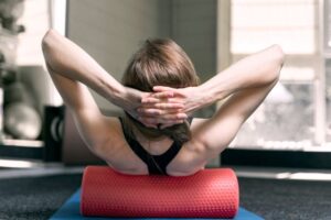 Woman laying on the floor doing stretches with a foam roller