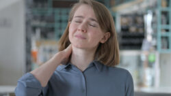 Young woman holding her sore neck