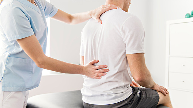 Man sitting on bench getting assessed by chiropractor