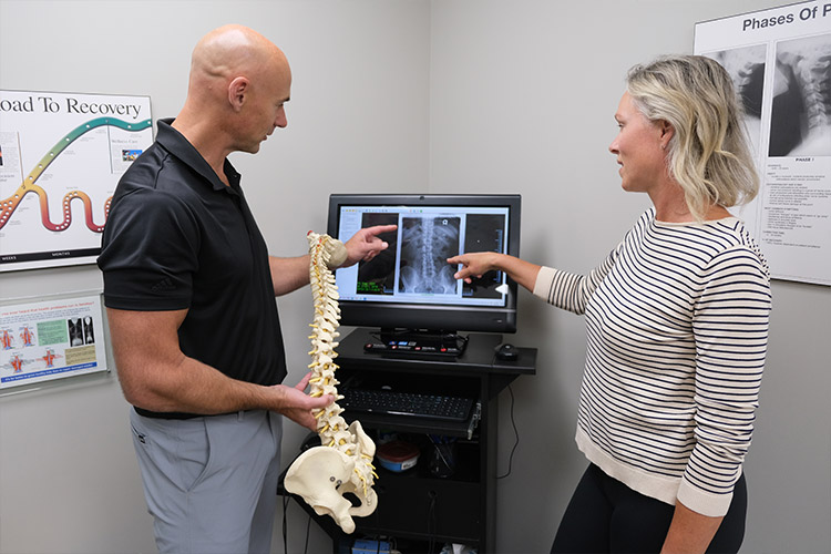 Dr. Aaron Cain talking with patient while looking at x-ray of spine