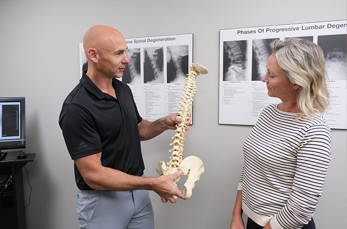 Chiropractic doctor showing patient a model of a spine