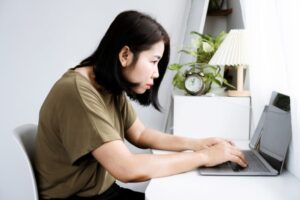 Woman sitting in front of a laptop with bad neck posture